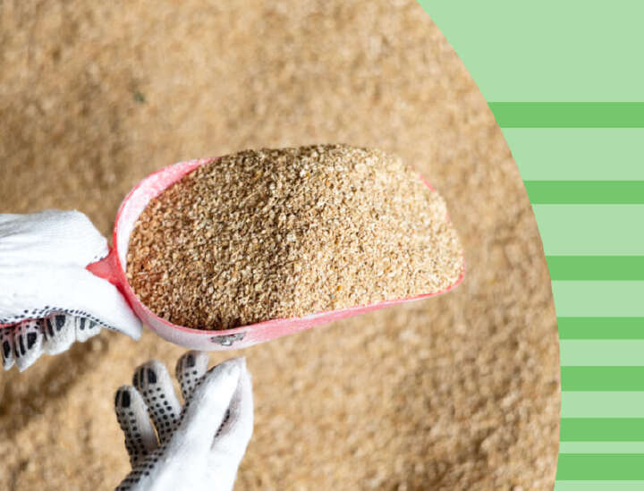 eine volle Futterschaufel mit Futter vor einem Futterberg